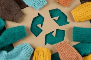Frecce del riciclo circondate da maglioni colorati