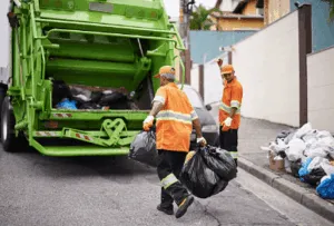 Operatori ecologici caricano sacchi nel camion verde