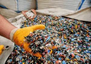 Mano guantata con frammenti di plastica riciclata