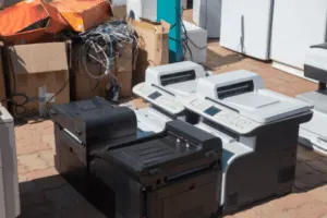 Stampanti usate accatastate all’aperto con cavi e scatole