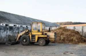 Pala meccanica gialla accanto a cumulo di fieno